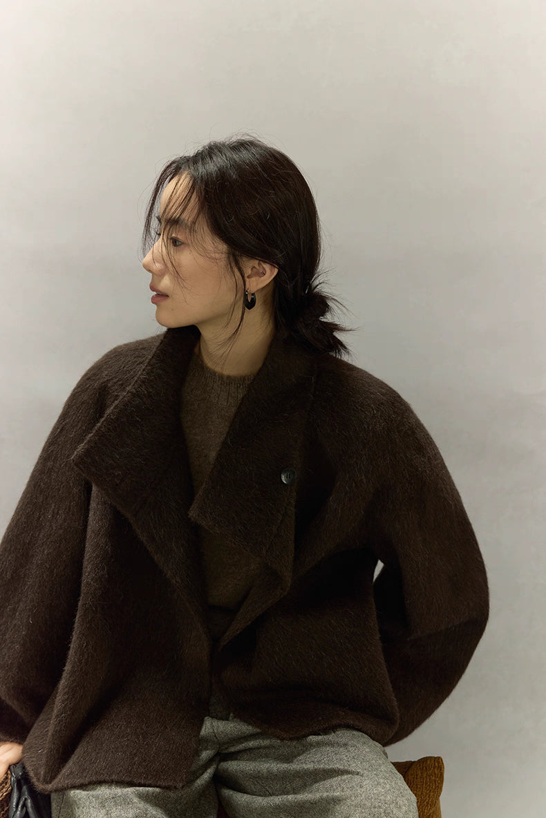 Seated side view of dark coffee brown alpaca wool jacket with wide lapel collar