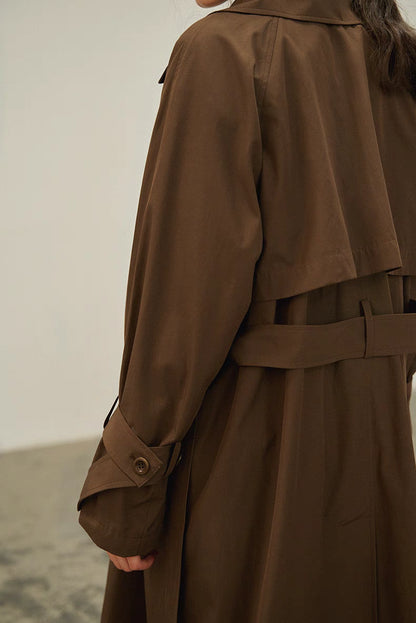 Dark brown trench coat back detail with storm flap, waist belt and clean tailored lines