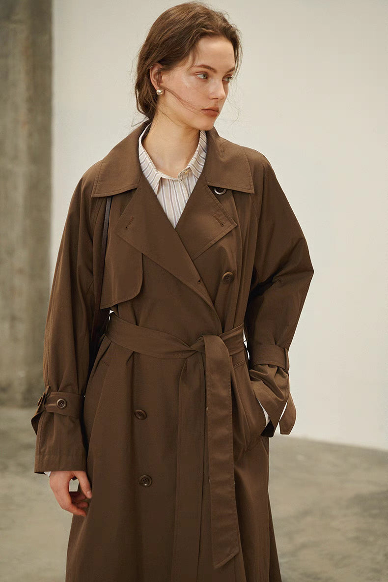 Dark brown trench coat front detail with tie belt, storm flap and double breasted buttons
