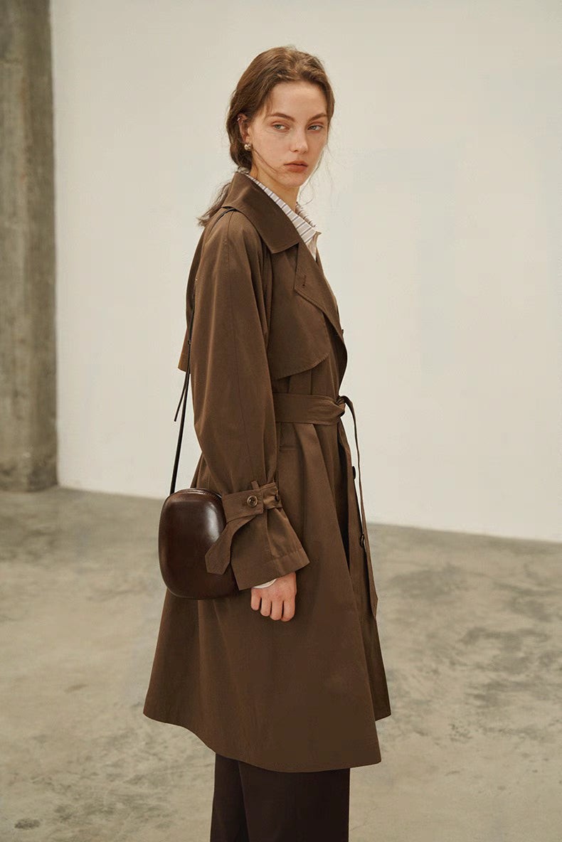 Dark brown short trench coat three quarter view highlighting cuff straps and structured fit