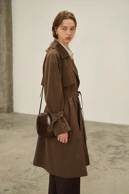 Dark brown short trench coat three quarter view highlighting cuff straps and structured fit