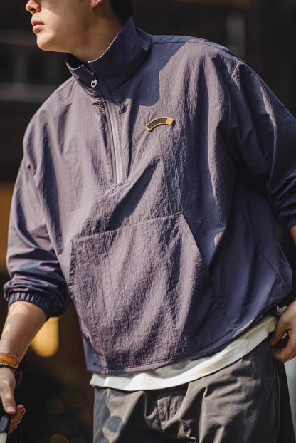 Model wearing dusty purple lightweight anorak jacket outdoors with half zip open