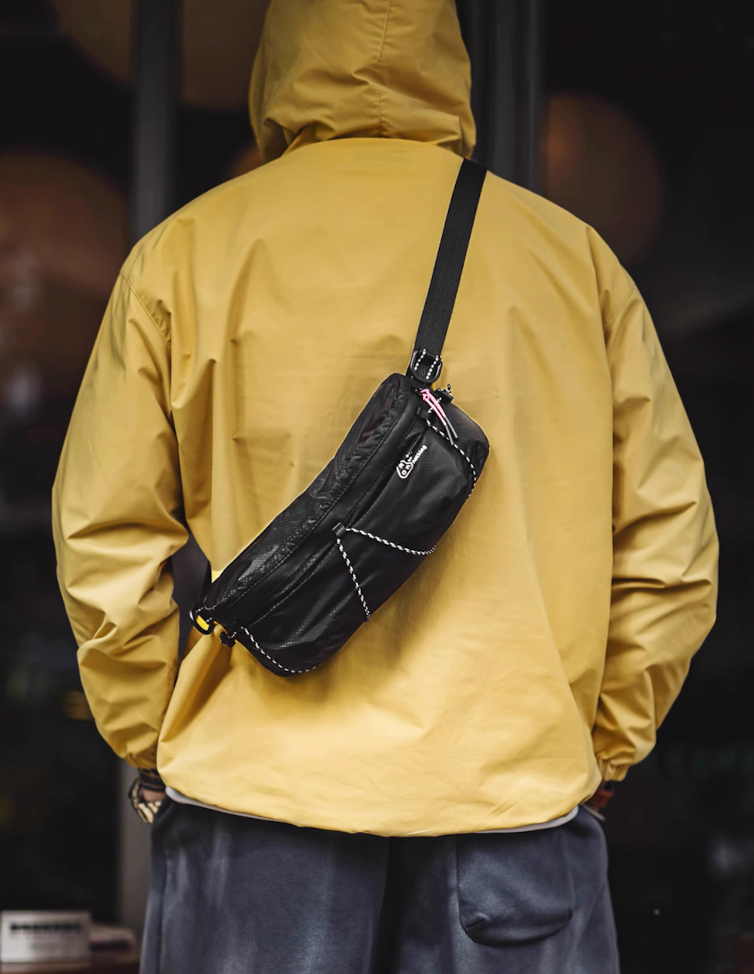 Model wearing AON black sling bag over shoulder with yellow jacket