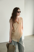 Three-quarter view of Apricot asymmetric sleeveless top showing bias-cut drape