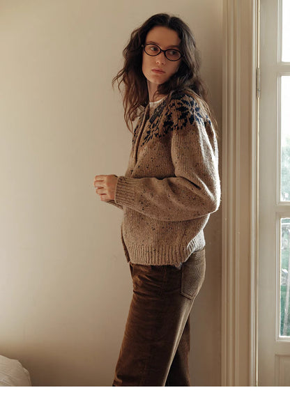 Khaki aran cable knit cardigan side profile view near window highlighting relaxed fit and textured wool knit