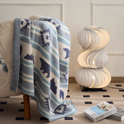 Blue Dream Bear blanket casually draped over armchair beside sculptural lamp in cozy living space