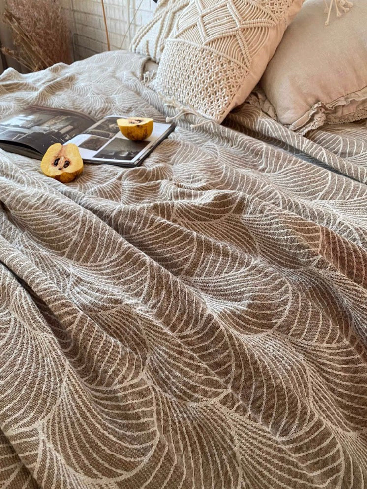 ArcWeave linen cotton handloom throw blanket in coffee color spread across bed with decorative pillows and cozy bedroom styling