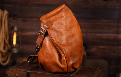 Side angle of caramel leather crossbody sling showing strap adjustment and soft grain.