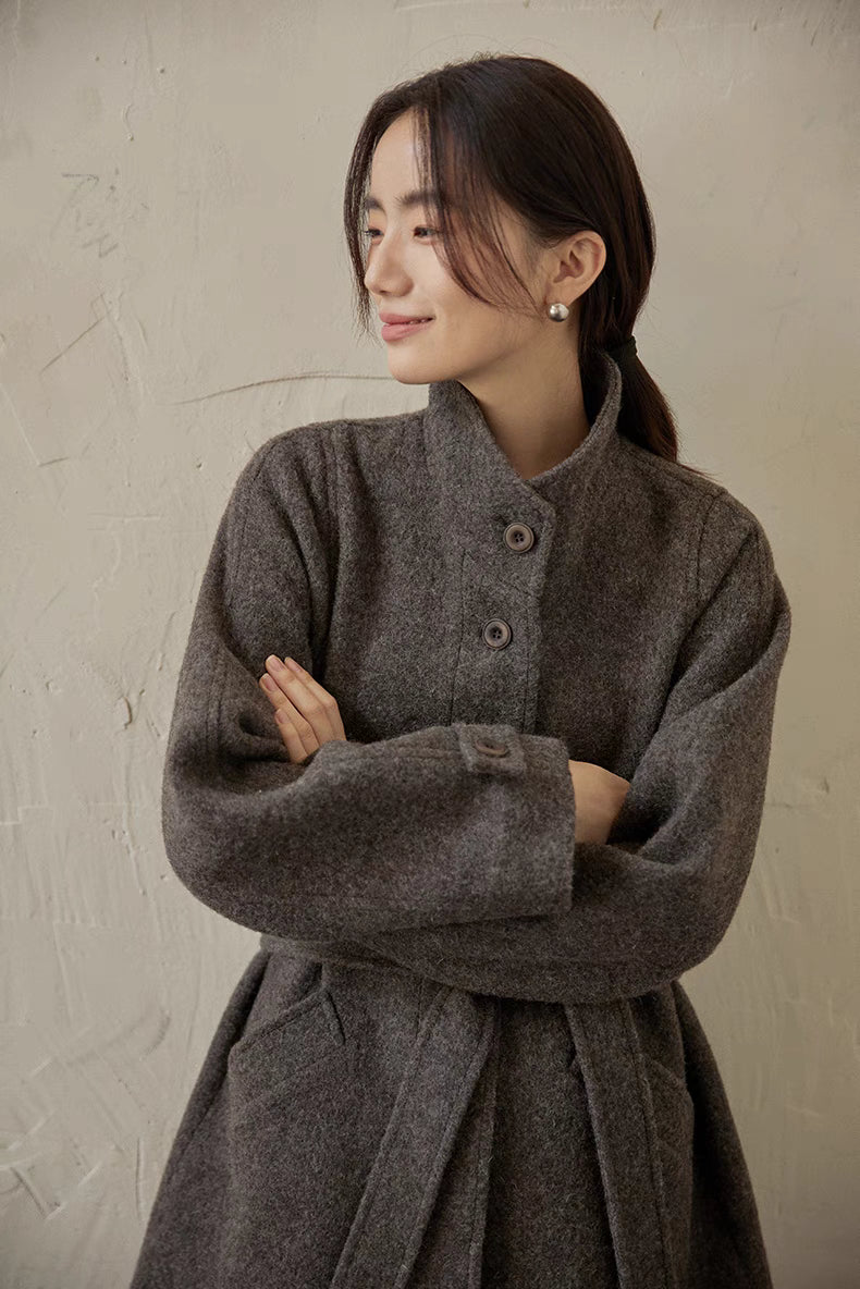 Gray wool belted jacket close-up with arms crossed highlighting sleeve cuff and button detail