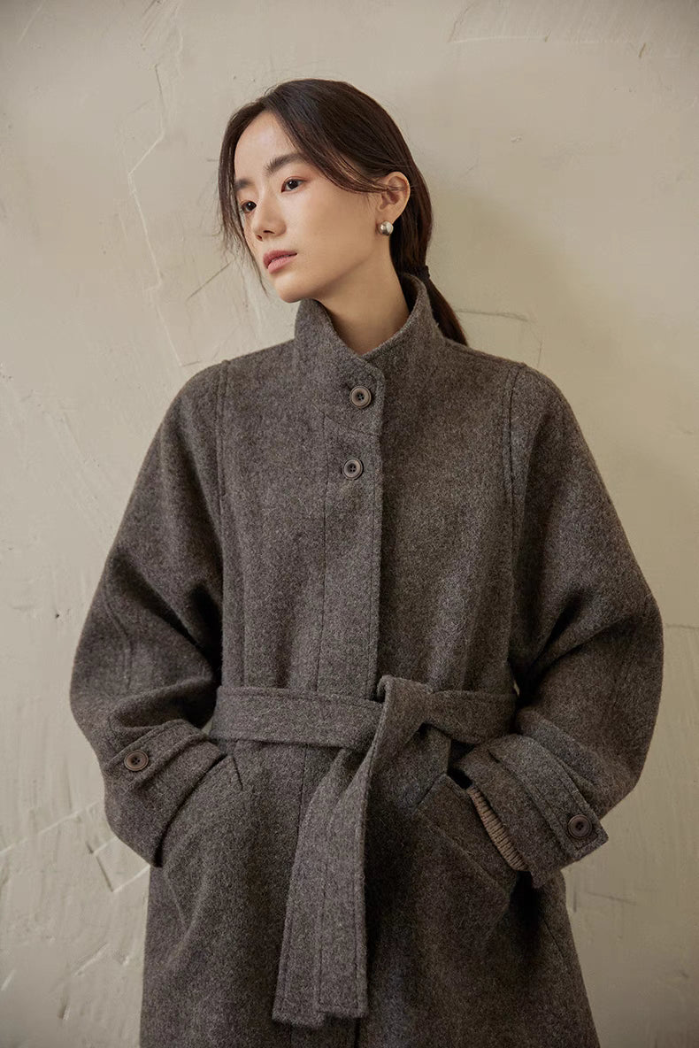 Gray wool jacket three-quarter view showing belt tie, button placket and structured silhouette
