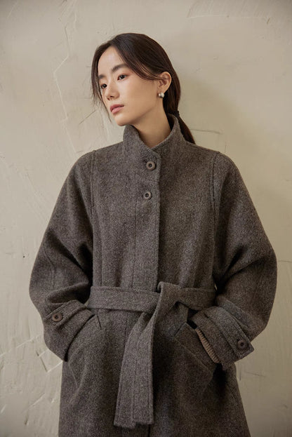 Gray wool jacket three-quarter view showing belt tie, button placket and structured silhouette
