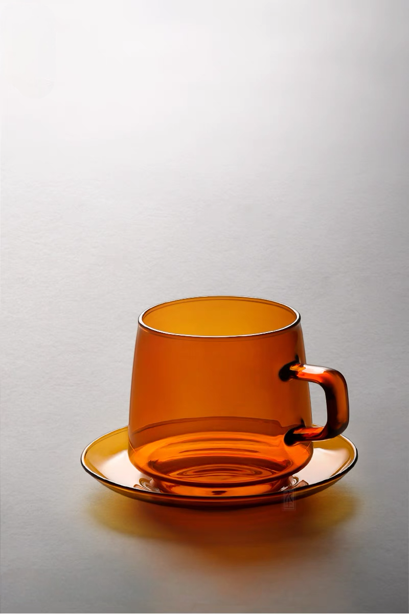 Amber Aurora Harmony glass cup and saucer set empty on neutral background highlighting warm translucent glass color