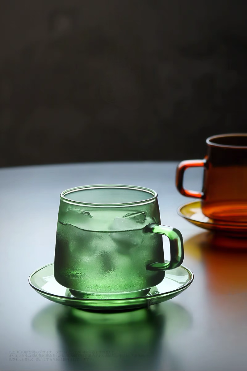 Green Aurora Harmony glass cup and saucer set with iced drink showing frosted condensation in modern lifestyle setting