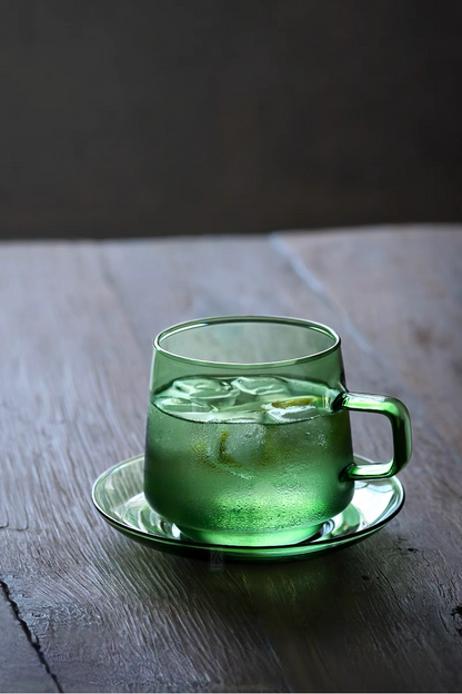 Green Aurora Harmony glass cup and saucer with iced beverage on wooden table showing textured condensation detail