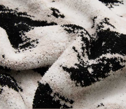 Close-up of black and white blanket surface showing dense fuzzy fibers and abstract pattern blending into soft texture