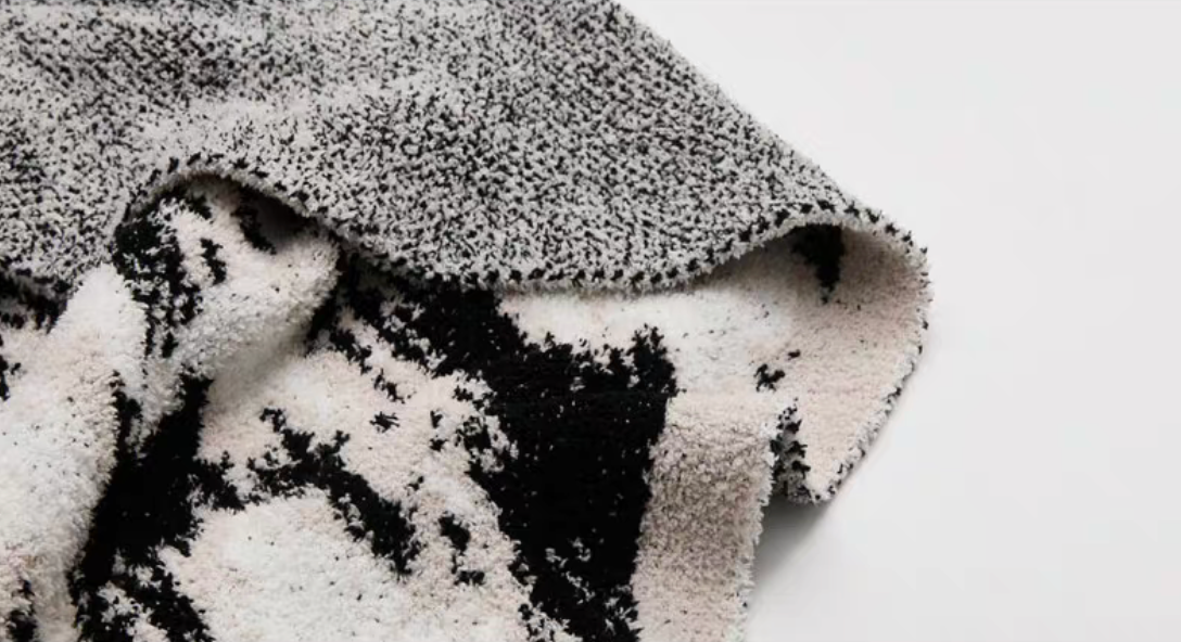 Detailed view of blanket corner revealing contrast between patterned front and gray-toned reverse backing