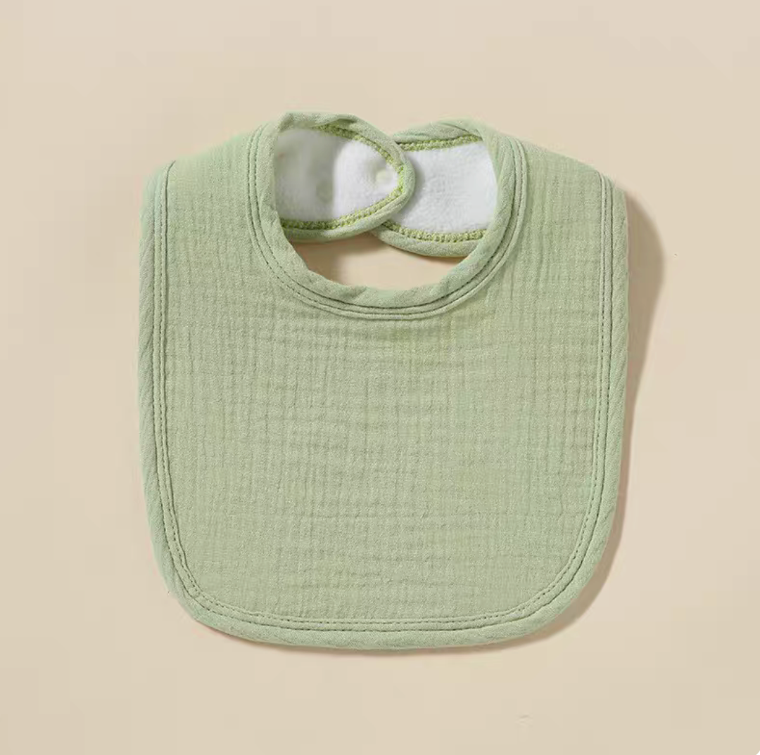 Green baby cotton gauze bib with soft breathable texture and rounded shape laid flat