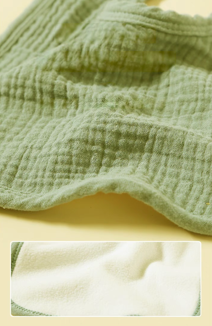 Green baby bib close-up showing cotton gauze texture and soft breathable fabric