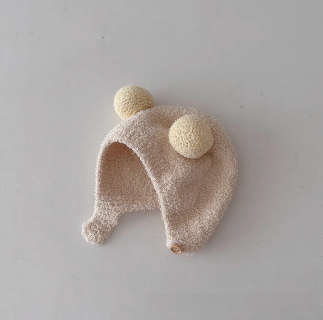 Beige baby pom pom hat with double pom poms soft fleece texture and ear protection design