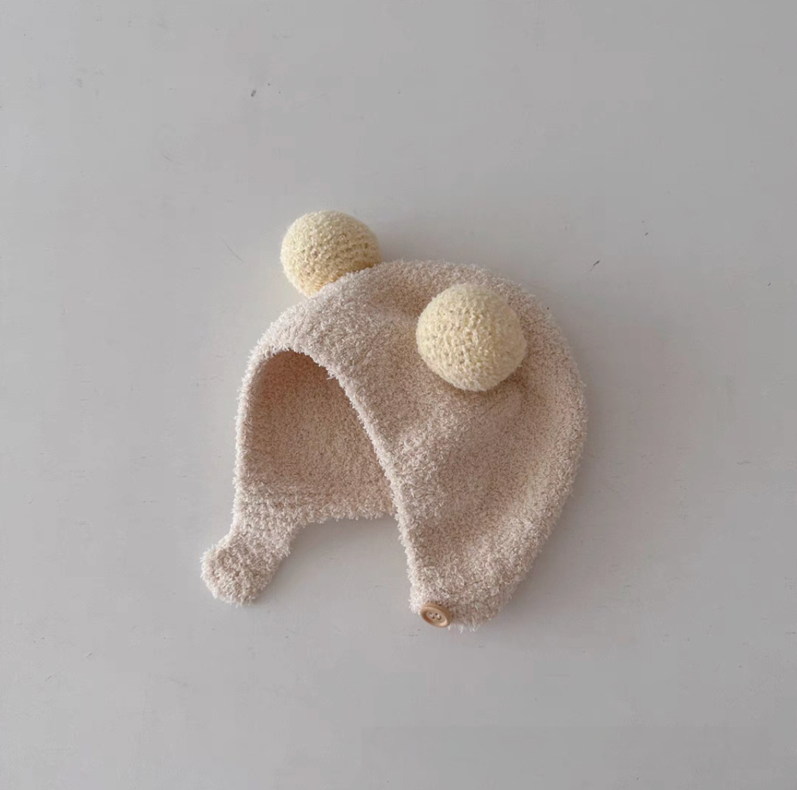 Beige baby pom pom hat with double pom poms soft fleece texture and ear protection design