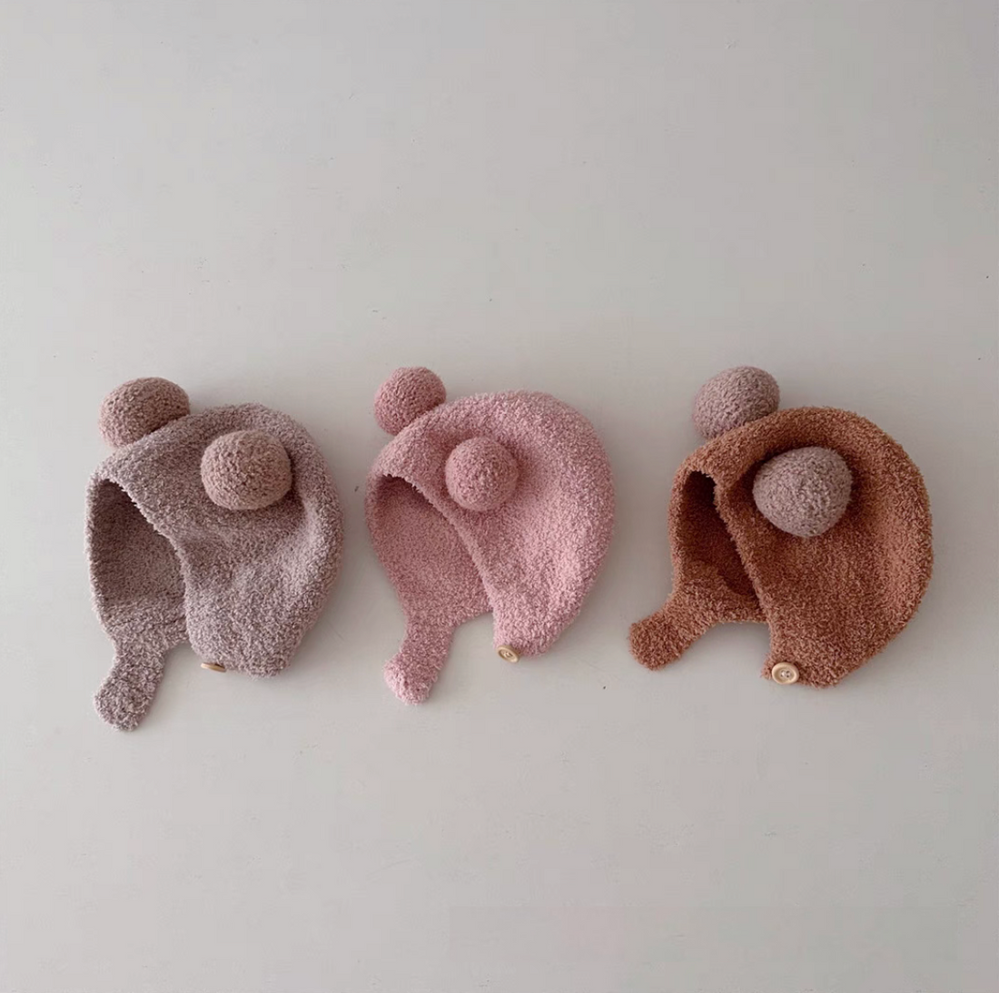 Baby ear protection pom pom hats in Beige, Coffee, Caramel, Pink, and soft neutral tones displayed together in multi-color overview