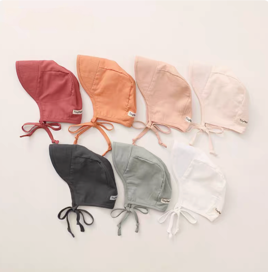 Multiple baby linen cotton sun hats in assorted colors arranged flat lay showing full collection