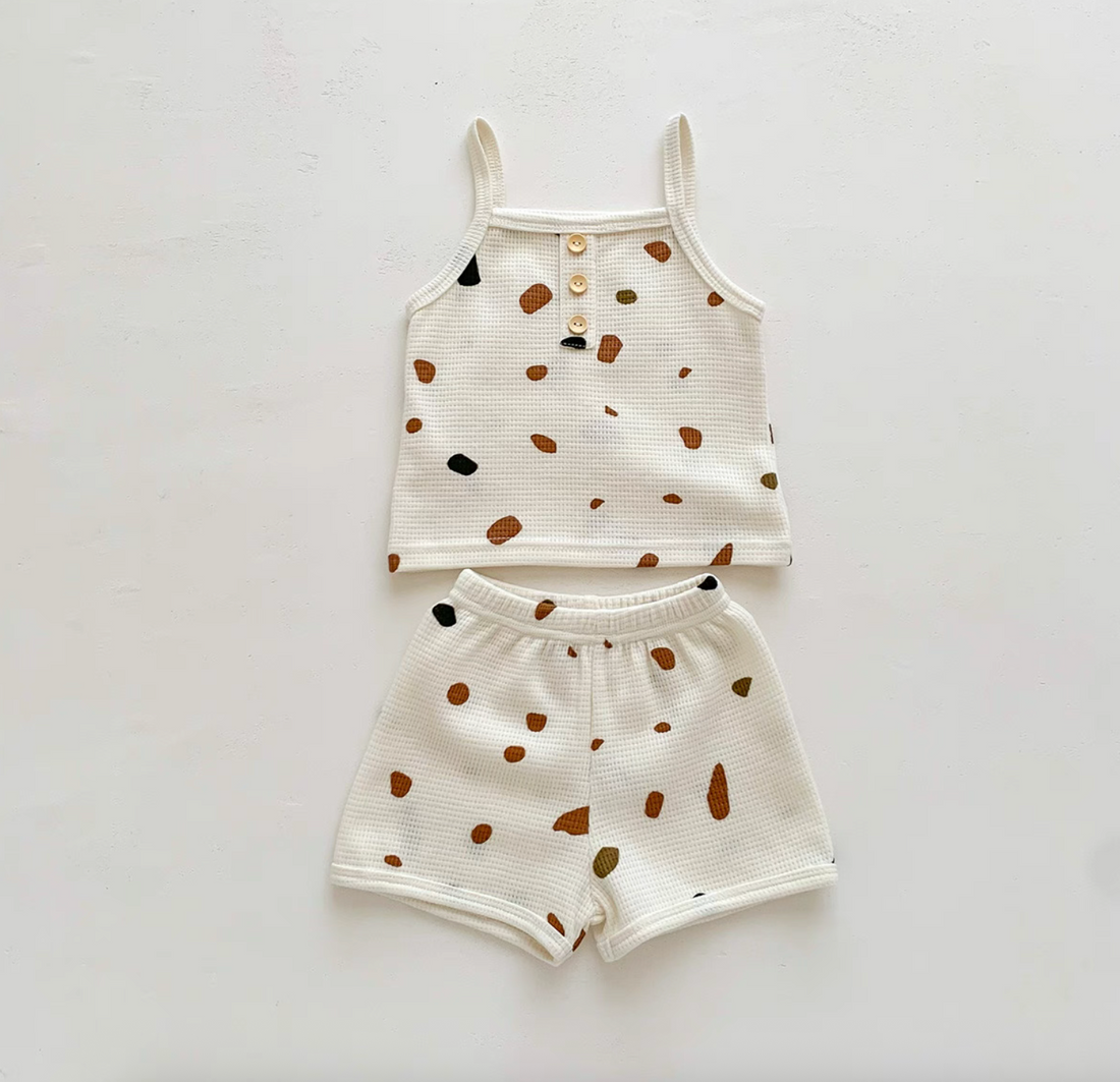 Flat lay of baby waffle knit set with colorful stone print tank and shorts