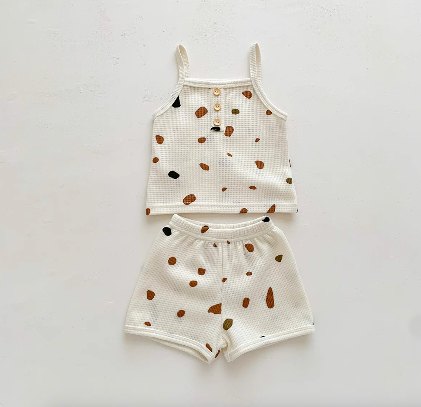 Flat lay of baby waffle knit set with colorful stone print tank and shorts