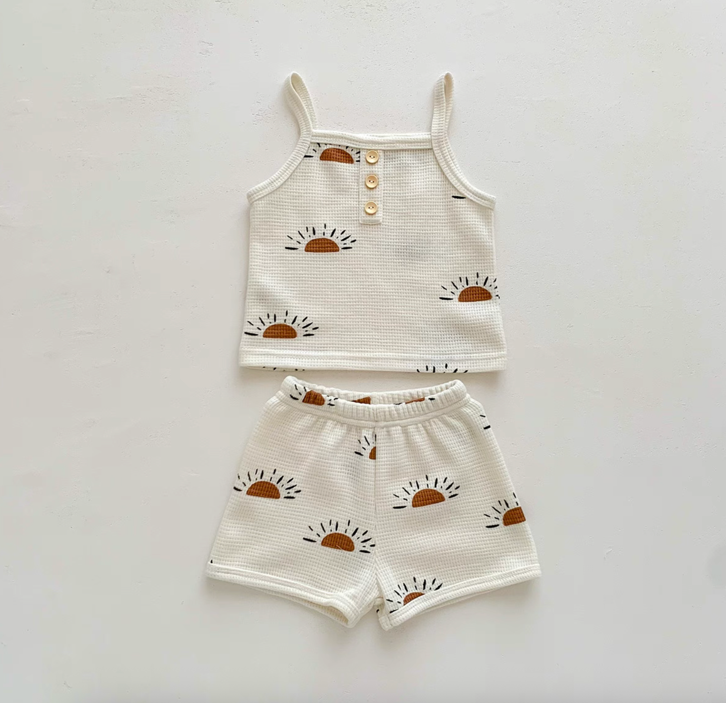 Flat lay of baby waffle knit set with sunshine sunrise print top and shorts