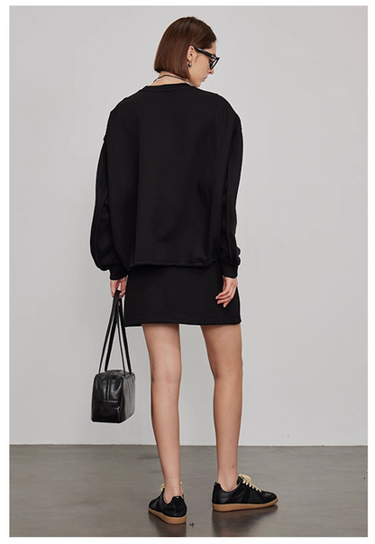 Back view of women’s oversized black sweatshirt with mini skirt casual loungewear