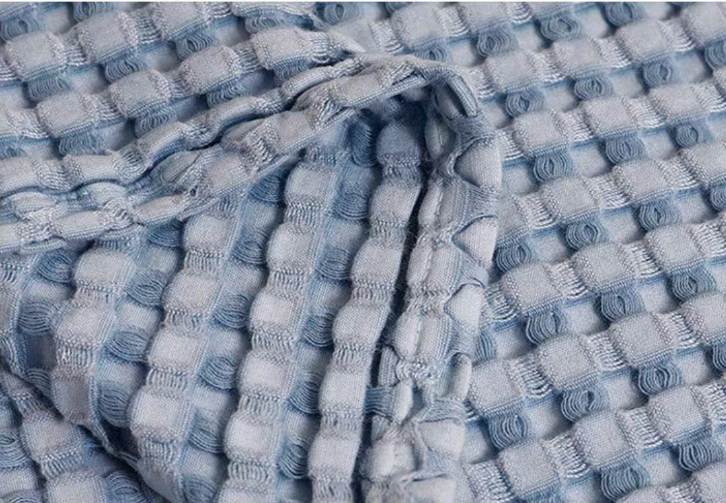 Close-up of blue bamboo fiber cotton waffle knit blanket texture highlighting soft breathable eco-friendly woven pattern