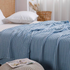 Blue bamboo fiber cotton waffle throw blanket draped across bed, breathable lightweight sofa throw with textured waffle knit design