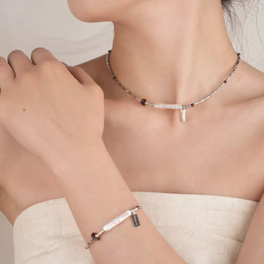 Model wearing Baroque Elegance Layered Necklace in garnet with matching bracelet and baroque pearl detail