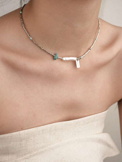 Close-up of model wearing Baroque Elegance Layered Necklace in turquoise with baroque pearl centerpiece
