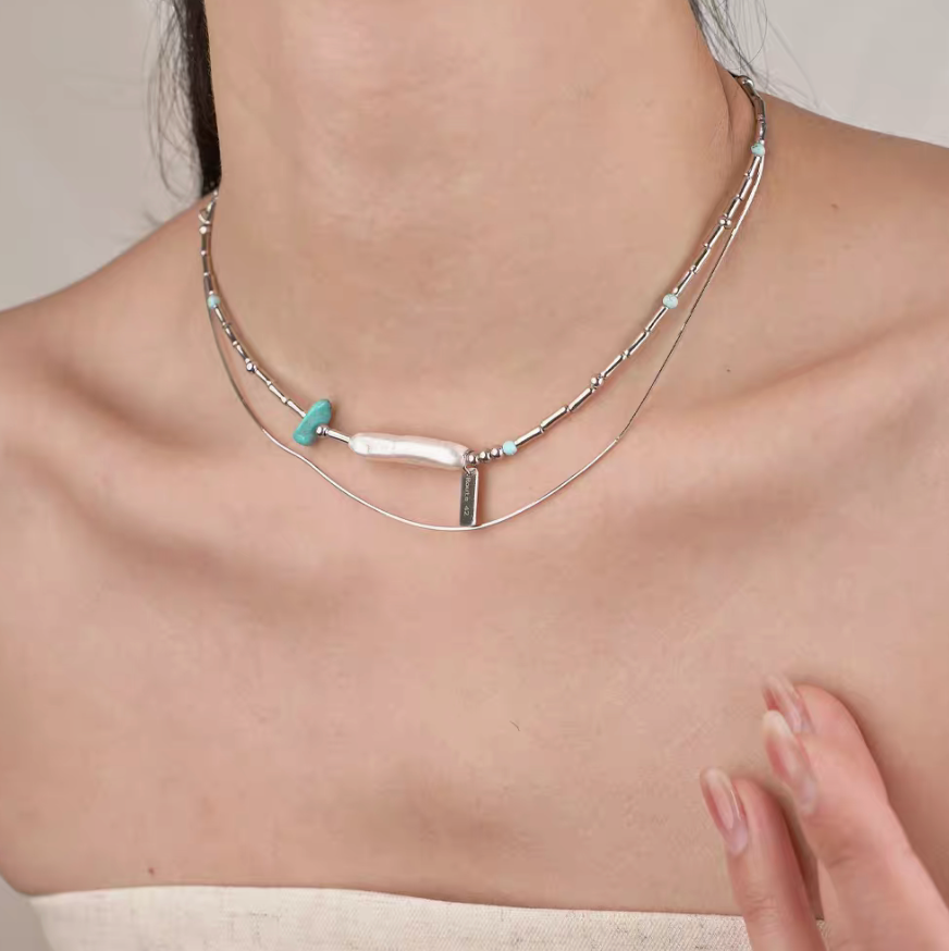 Model wearing Baroque Elegance Layered Necklace in turquoise with baroque pearl and layered silver chain