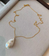 Sculptural baroque freshwater pearl necklace with large natural pearl pendant and delicate gold chain on display box