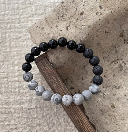 Black Beach Onyx Volcanic Stone Bracelet with black onyx, volcanic stone and gray map stone beads on textured wood surface
