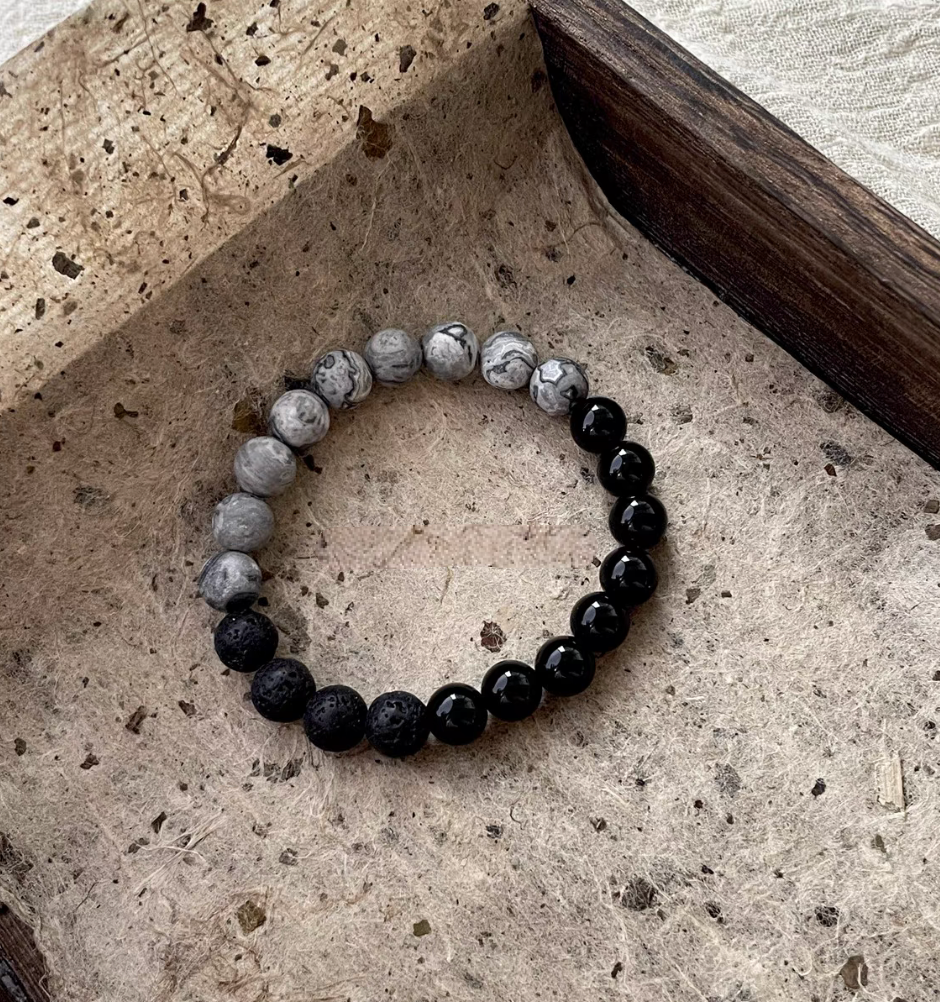 Flat lay of Black Beach Onyx Volcanic Stone Bracelet with black onyx, volcanic stone and gray map stone beads on natural textured background
