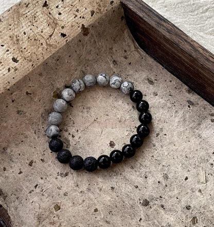 Flat lay of Black Beach Onyx Volcanic Stone Bracelet with black onyx, volcanic stone and gray map stone beads on natural textured background