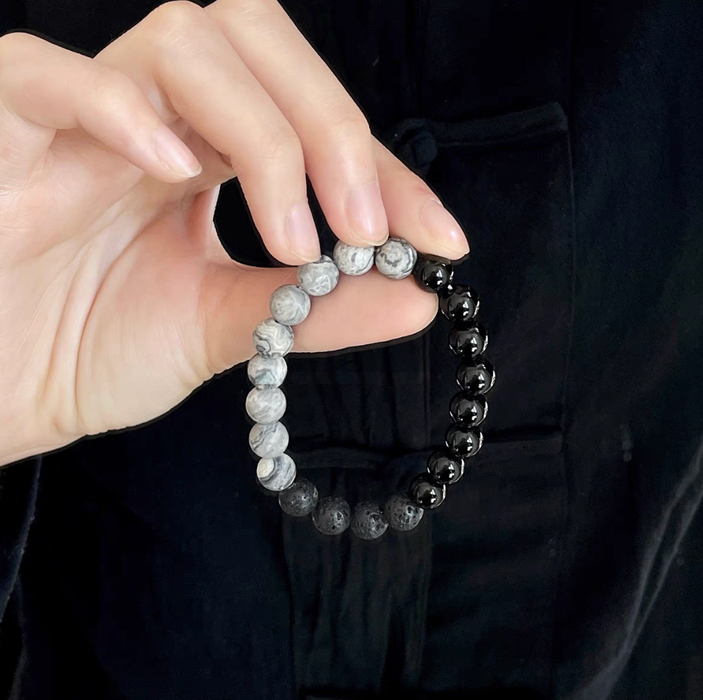 Hand holding Black Beach Onyx Volcanic Stone Bracelet featuring black onyx, volcanic stone and gray map stone beads