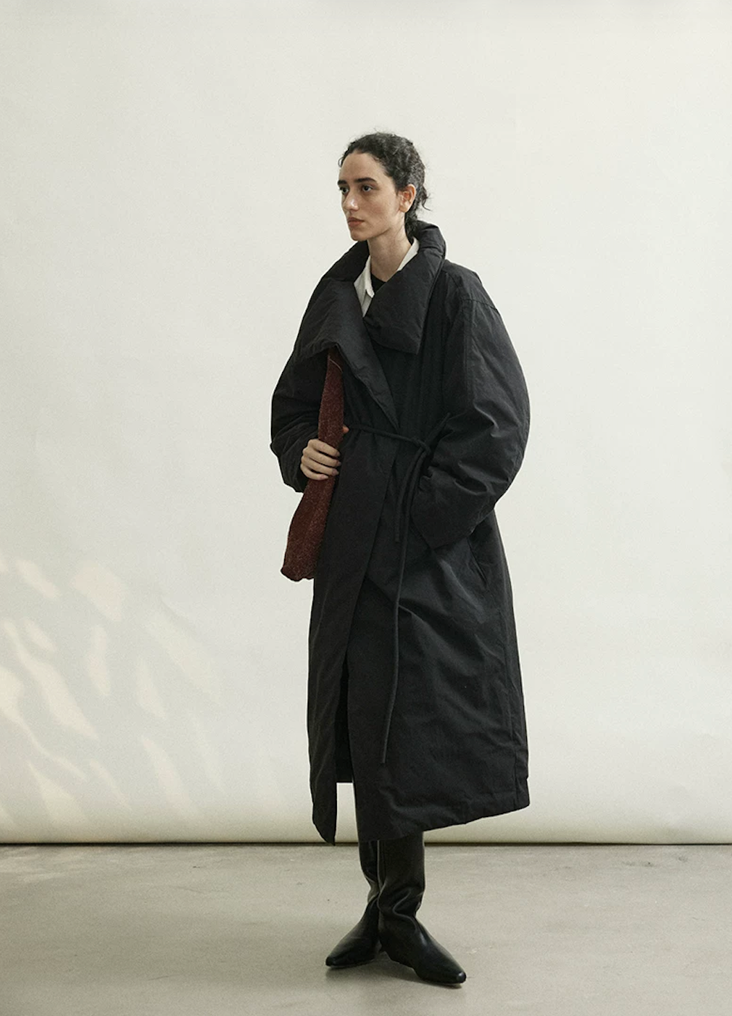 Full-length view of a Black long down coat cinched at the waist with its rope belt