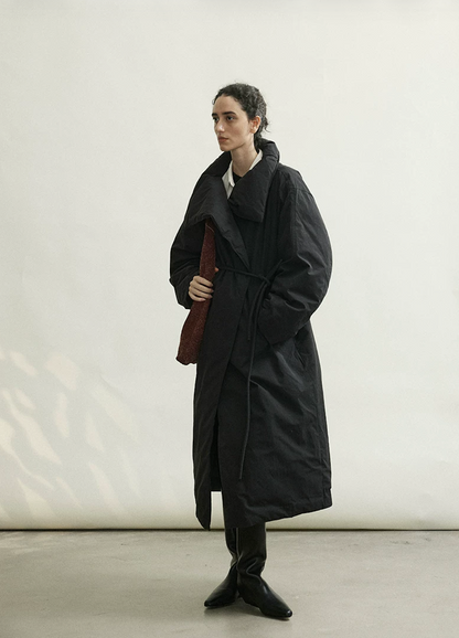 Full-length view of a Black long down coat cinched at the waist with its rope belt