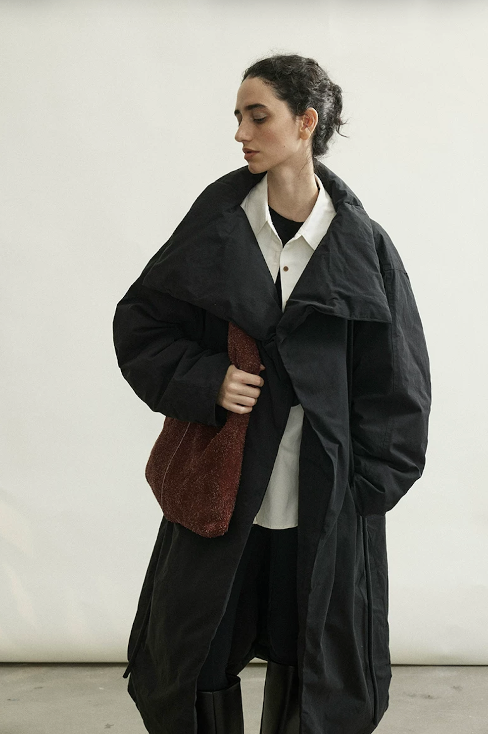 Black long cotton down coat with oversized padded lapel collar, worn loosely closed