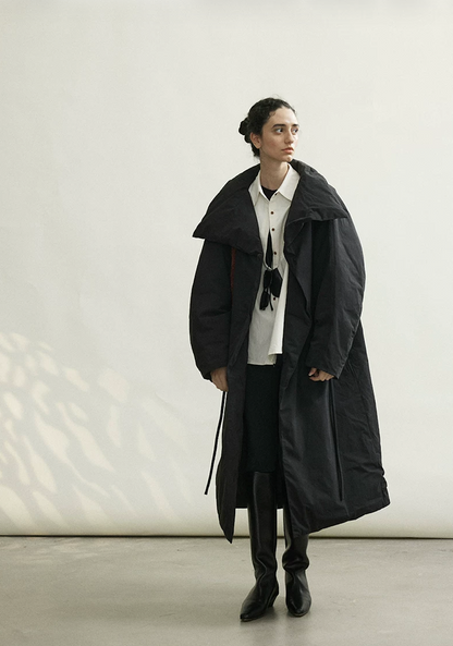 Full-length view of a Black oversized down coat worn open with the rope belt hanging loose