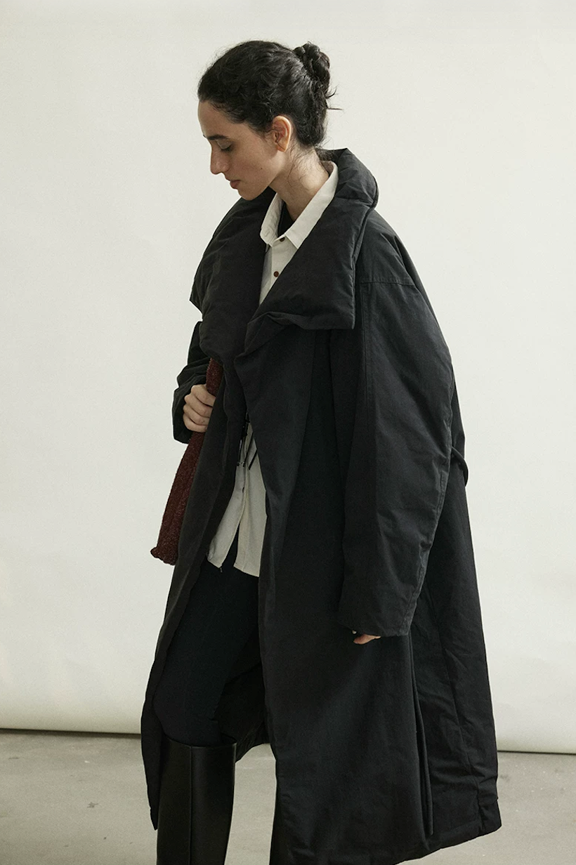 Side view of a Black crinkled cotton down coat in motion, showing dropped shoulders