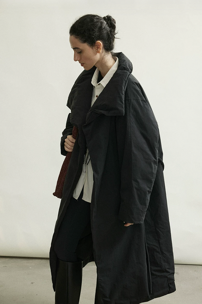 Side view of a Black crinkled cotton down coat in motion, showing dropped shoulders