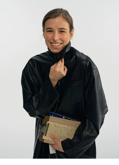 Model flipping up the collar of a black oversized faux leather jacket