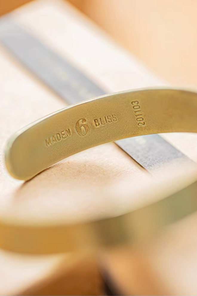 Close-up of inner side of brass cuff bracelet showing Made in Bliss engraving and serial number detail