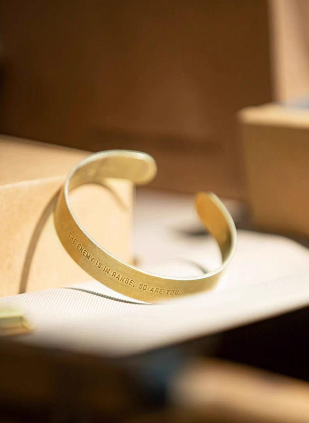Brass cuff bracelet with engraved message placed on surface in warm lifestyle setting