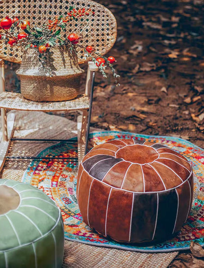 Camel faux leather pouf in outdoor setting with rug and chair